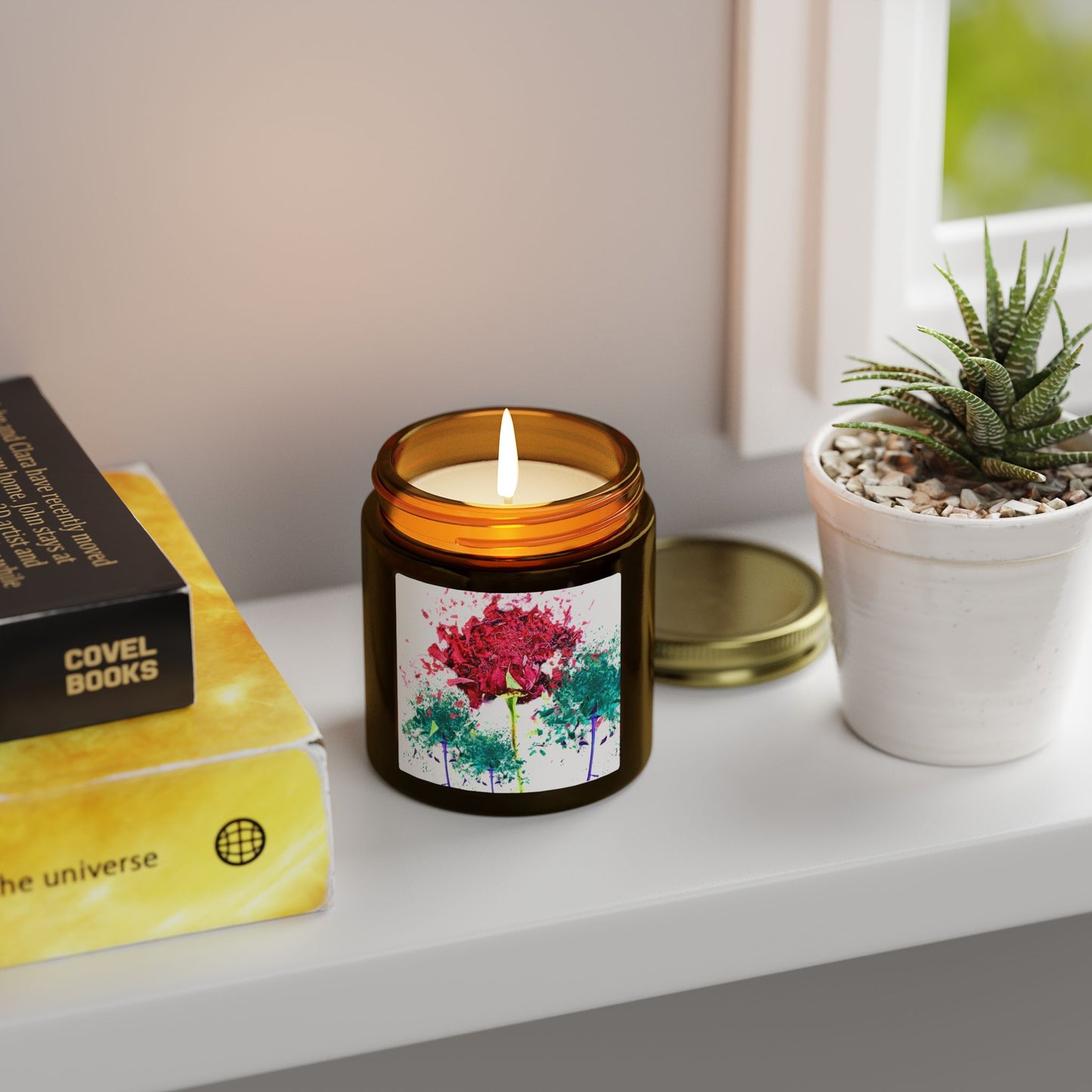 Candle with a floral label on a shelf next to a book and plant