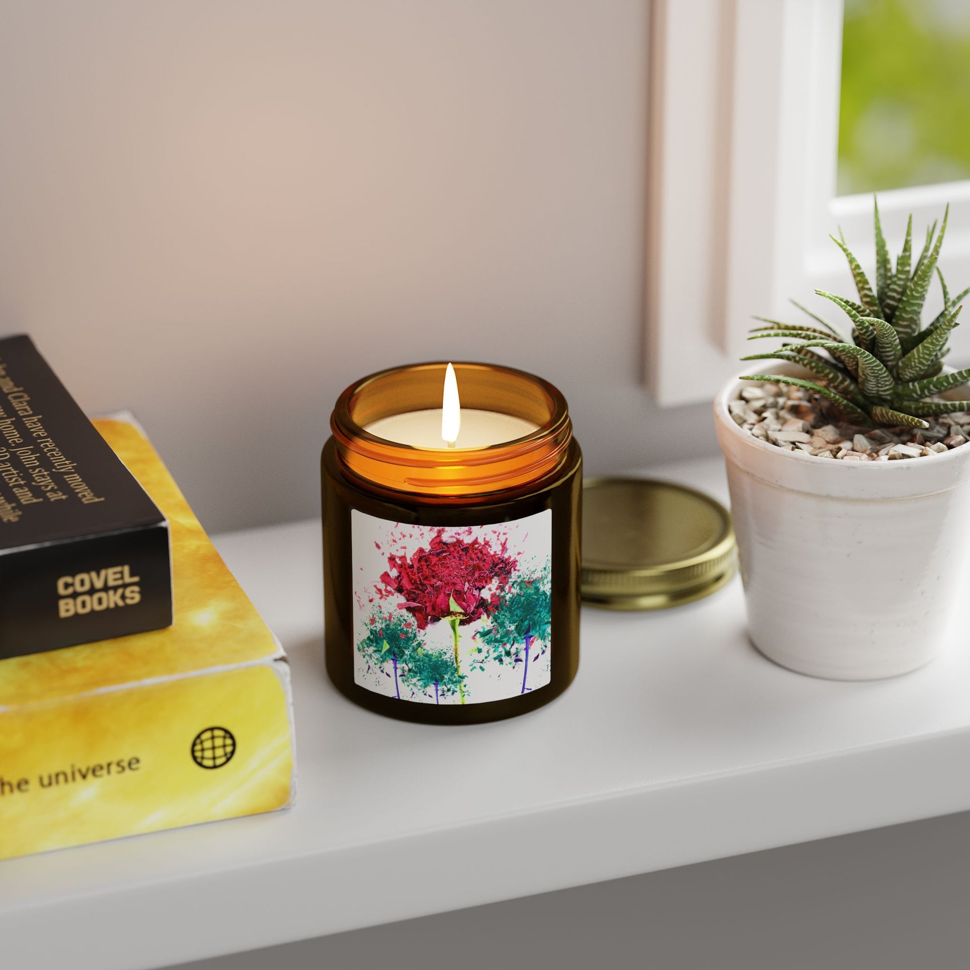 Candle with a floral label on a shelf next to a book and plant