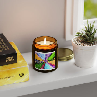 Candle with a colorful label on a shelf next to a book and plant
